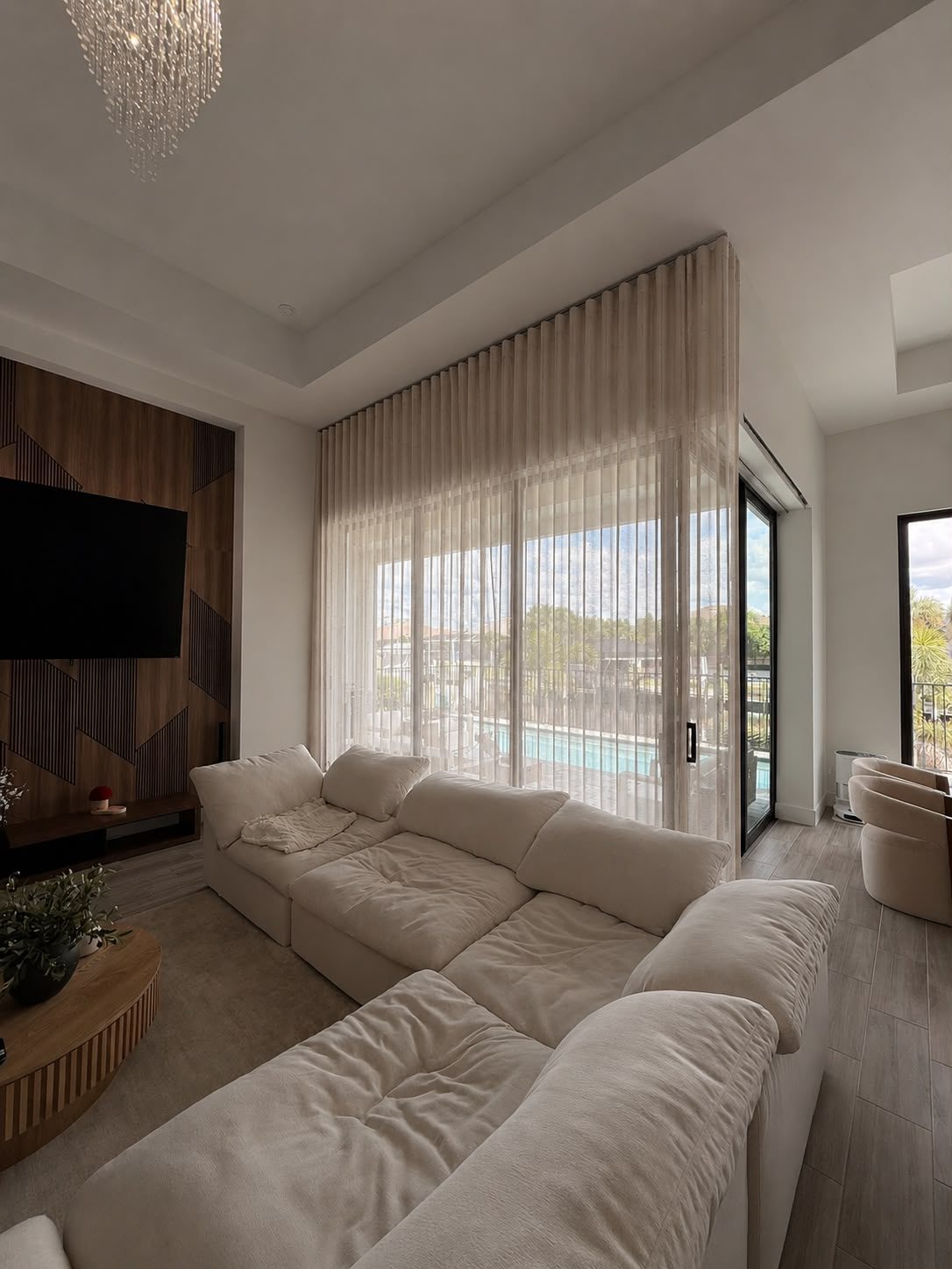 Floor-to-ceiling sheer wave drapery on sliding glass doors in a living room with a pool view