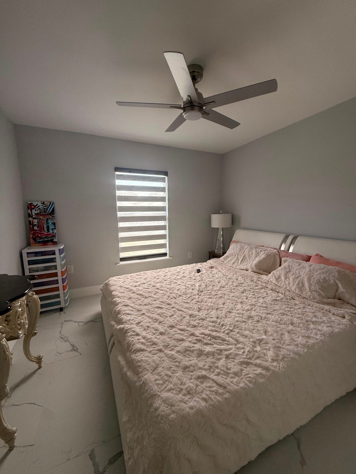 Gray zebra blind filtering daylight in a bedroom with marble floors