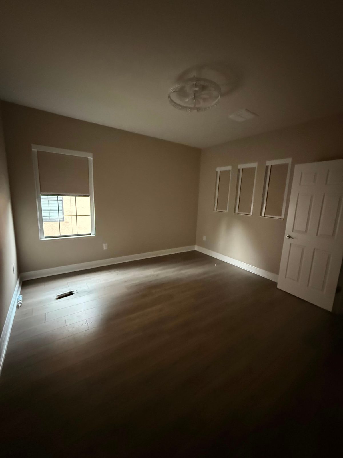 Beige room-darkening roller shades on four bedroom windows in a newly finished home