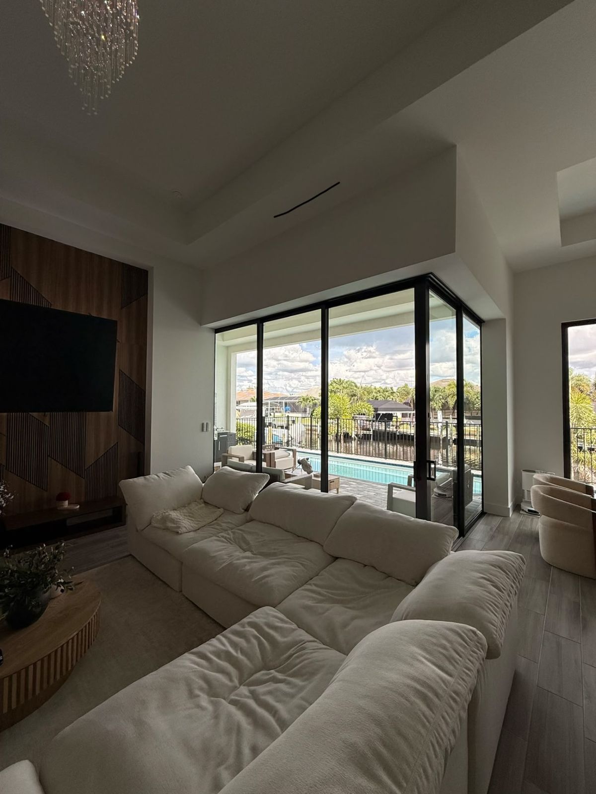 Zebra blinds raised on a corner sliding glass door system opening to a pool and canal in a modern home